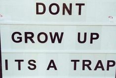 two signs that say don't grow up, it's a trap