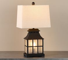 a lamp that is on top of a table with a white shade over the light