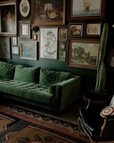 a green couch sitting in front of pictures on the wall