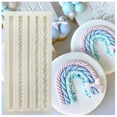 three decorated cookies sitting next to each other on top of a white tablecloth with blue and pink icing