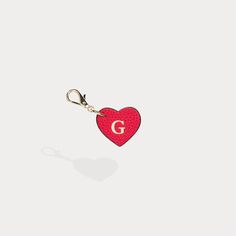 a red heart shaped keychain with the letter g on it's side