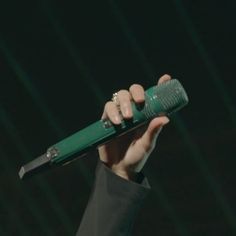 a person holding a green object in their hand with the light on it's side