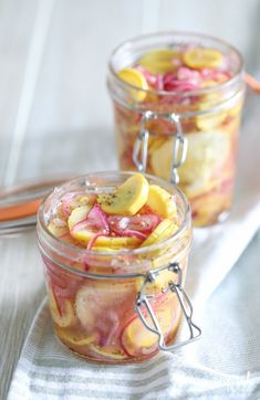 two jars filled with pickled fruit on top of a table