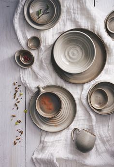 a table topped with plates and cups filled with saucers on top of a white cloth