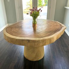 a wooden table sitting on top of a hard wood floor next to a doorway with a potted plant in it