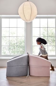 a woman sitting on top of two pink and grey beds