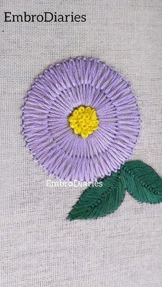 a close up of a flower on a white surface with green leaves and the words embroiderydiaries written below it