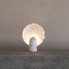 a white marble lamp sitting on top of a cement wall next to a light bulb