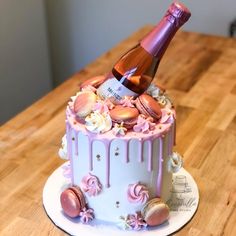 a cake with pink frosting and an ice cream cone on top that has a bottle of champagne in it