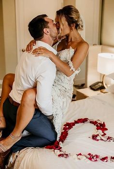 a bride and groom kissing on the bed