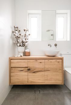 a bathroom with a sink, mirror and wooden cabinet in front of the toilet area