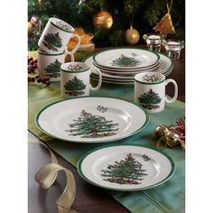 a christmas table setting with plates, cups and saucers decorated with evergreen tree designs