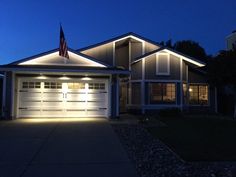 an american flag is lit up on the front of a house at night in this suburban neighborhood