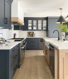 a kitchen with blue cabinets and white counter tops, wood flooring and stainless steel appliances