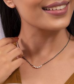 a woman wearing a black and white necklace with diamonds on the bottom of her neck