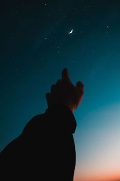 a hand reaching up to the sky at night with a crescent moon in the background