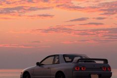 a car parked on the beach at sunset with its rear lights turned to be red