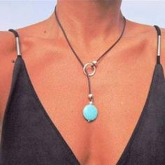 a woman wearing a necklace with a turquoise stone