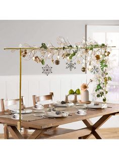 a wooden table topped with white plates and cups next to a plant hanging from the ceiling