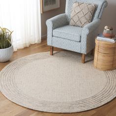 a living room with a chair, rug and potted plant on the side table