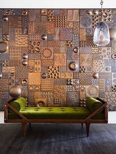 a green couch sitting in front of a wall covered with metal circles and circles on it