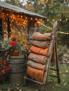 a wooden chair sitting next to a barrel filled with flowers and blankets on top of it