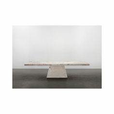 a white marble table sitting on top of a cement floor next to an empty wall