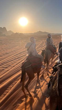 three people are riding camels in the desert