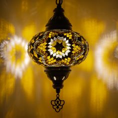 a lamp hanging from the ceiling in a room with yellow and white lights behind it