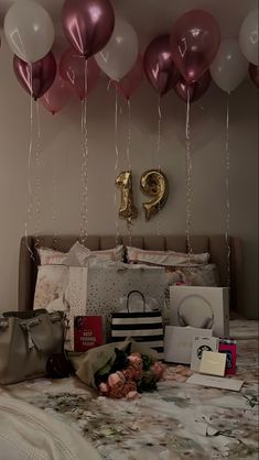 a bed with pink and white balloons hanging from it's headboard, along with other items