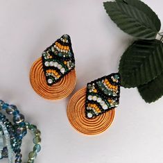 two pairs of beaded earrings sitting on top of a table next to a plant