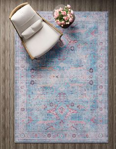 a blue rug with a white chair and pink flowers