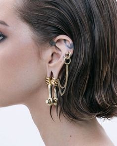 a close up of a woman's face wearing gold ear cuffs and piercings