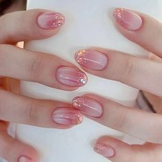 a woman's hands with pink and gold manies on their nails, holding a white box