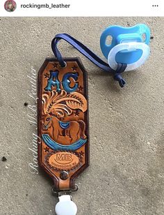 a wooden keychain with a blue pacifier attached to it's side