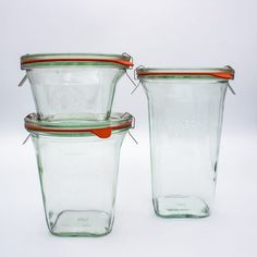 three glass containers with lids are stacked on top of each other and one is empty