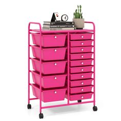 a pink cart with lots of drawers on it and a potted plant next to it