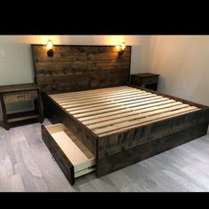 a bed with drawers underneath it and lights on the headboard, along with two night stands