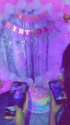 a woman holding up her cell phone in front of a birthday cake