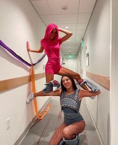 two women are doing aerial tricks in an office hallway, one is holding on to the other's leg