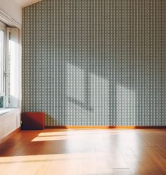 an empty room with wood flooring and wall coverings in the sunlight from a window