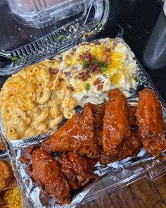 chicken wings, macaroni and cheese on tin foil with other food items in plastic containers