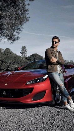 a man sitting on the hood of a red sports car