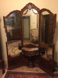 an ornate wooden mirror sitting on top of a rug next to a dresser and chair