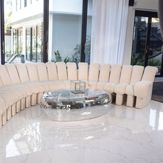 a large white couch sitting on top of a marble floor in front of a window