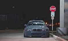 a silver car parked in front of a stop sign and street sign at night time