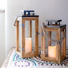 two wooden lanterns sitting on top of a table next to each other with candles in them