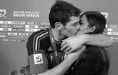 a man and woman kissing each other in front of a wall with trophies on it