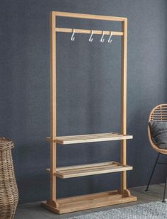 a wooden coat rack with two shelves and three hooks on the top, next to a wicker chair