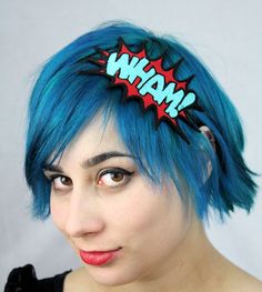 a woman with blue hair wearing a red and black headband that says man on it